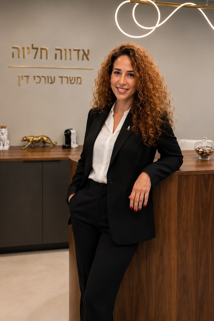עו״ד אדווה חליוה במשרדה — עומדת ליד דלפק הקבלה, על הקיר שלט הזהב של המשרד